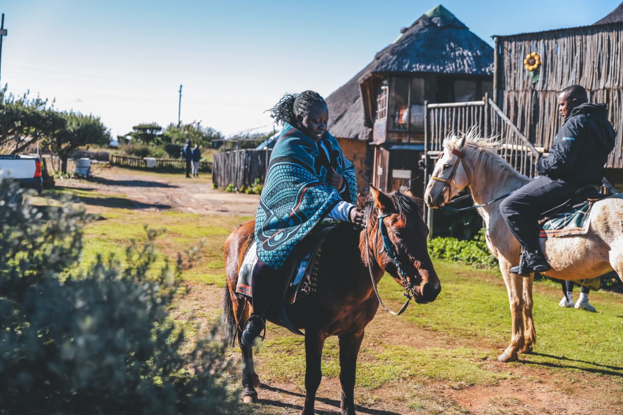 Two people riding horses in rural village