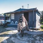 Person in traditional blanket walking towards rural home