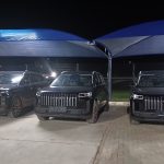 Three black SUVs parked under canopy at night
