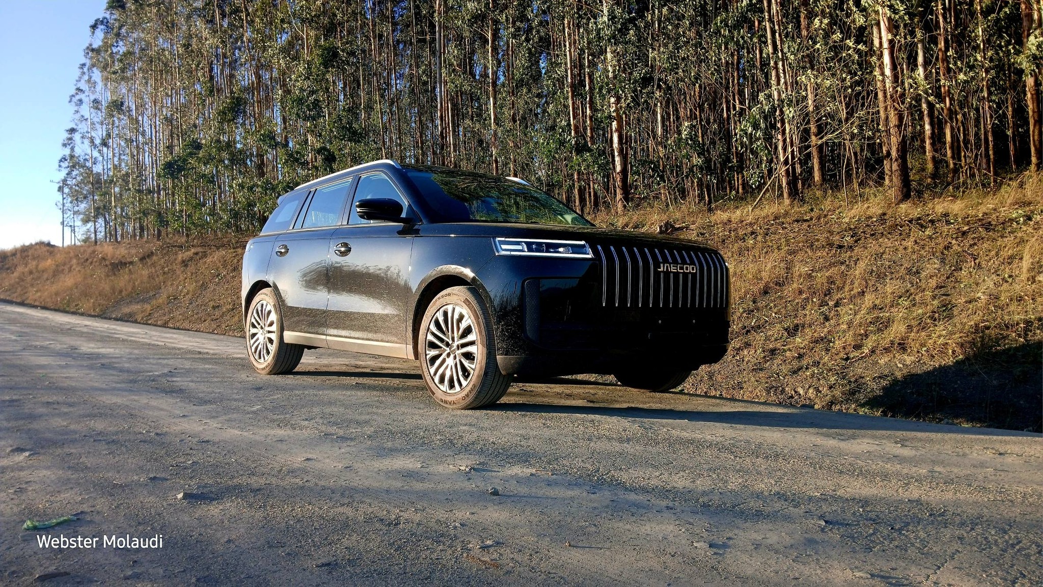 Black Jaecoo SUV on gravel forest road