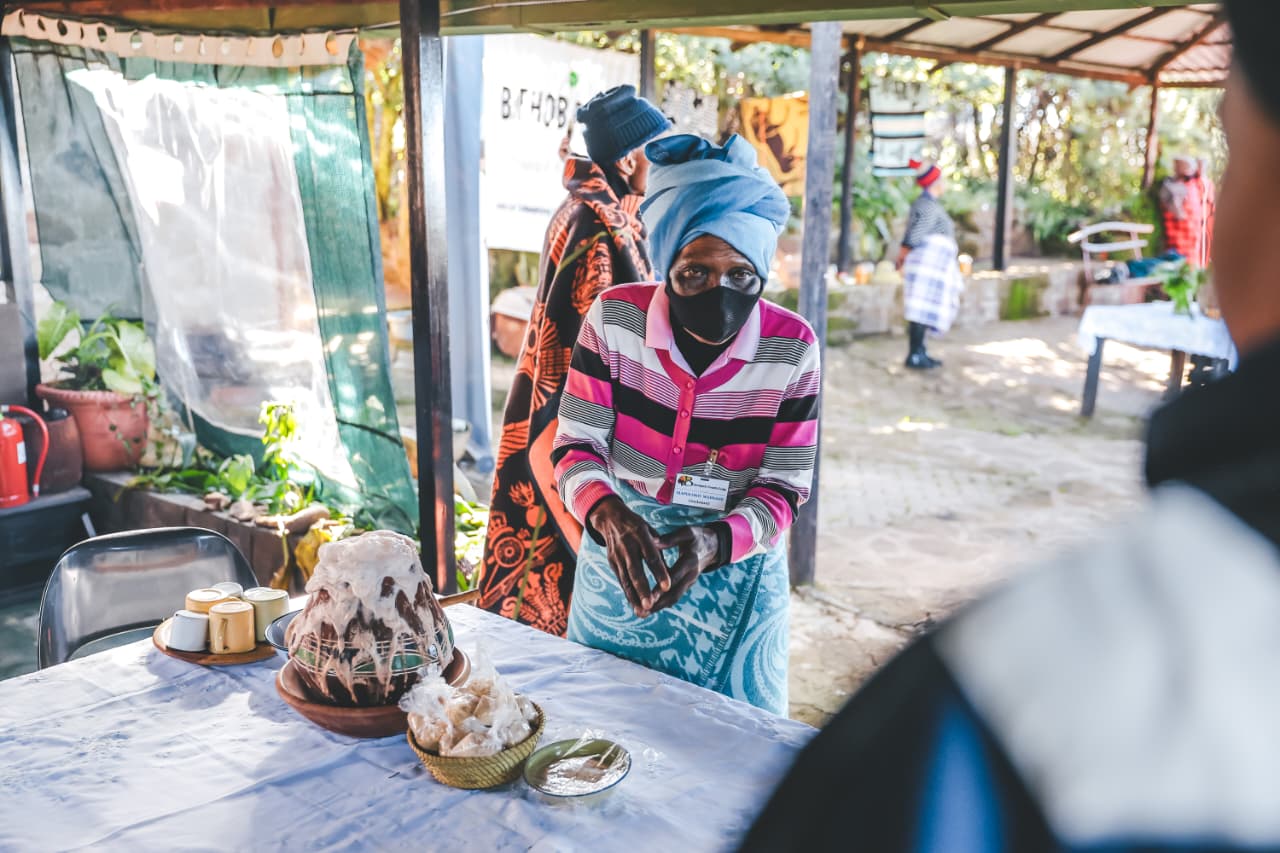 Woman in mask serving cake at outdoor gathering