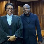 Two people standing in a wood-panelled courtroom