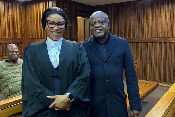 Two people standing in a wood-panelled courtroom