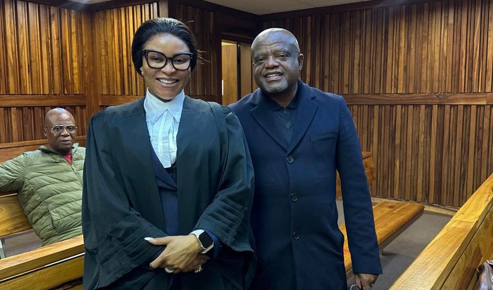 Two people standing in a wood-panelled courtroom