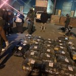Officials inspect seized packages at warehouse at night
