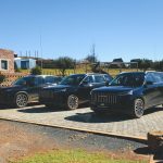 Three black SUVs parked outside rural lodge