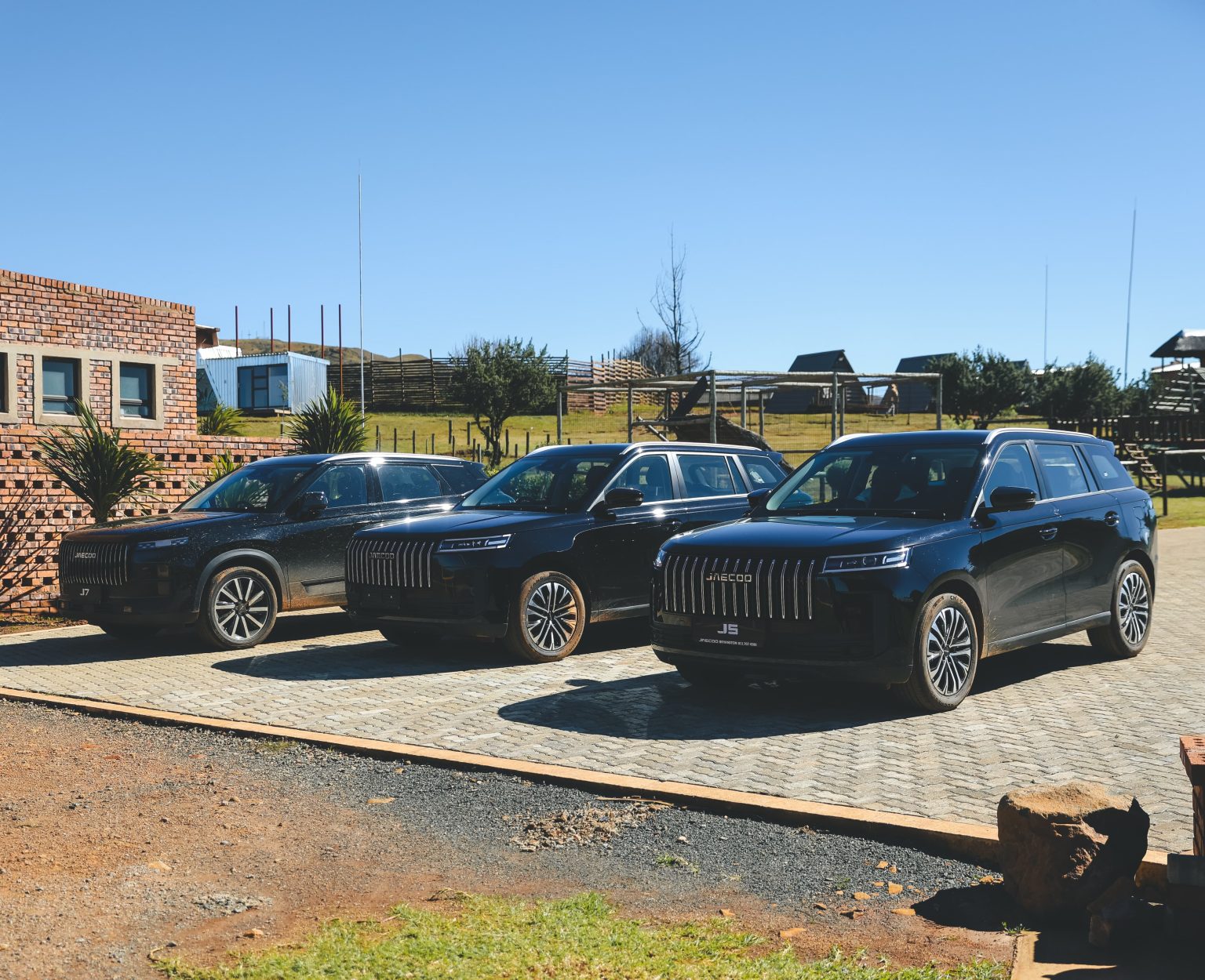 Three black SUVs parked outside rural lodge