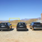 Three black SUVs overlooking mountain landscape