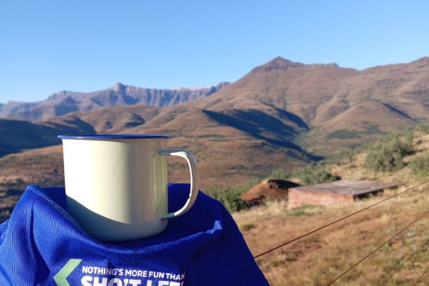Enamel mug on cap overlooking mountain landscape