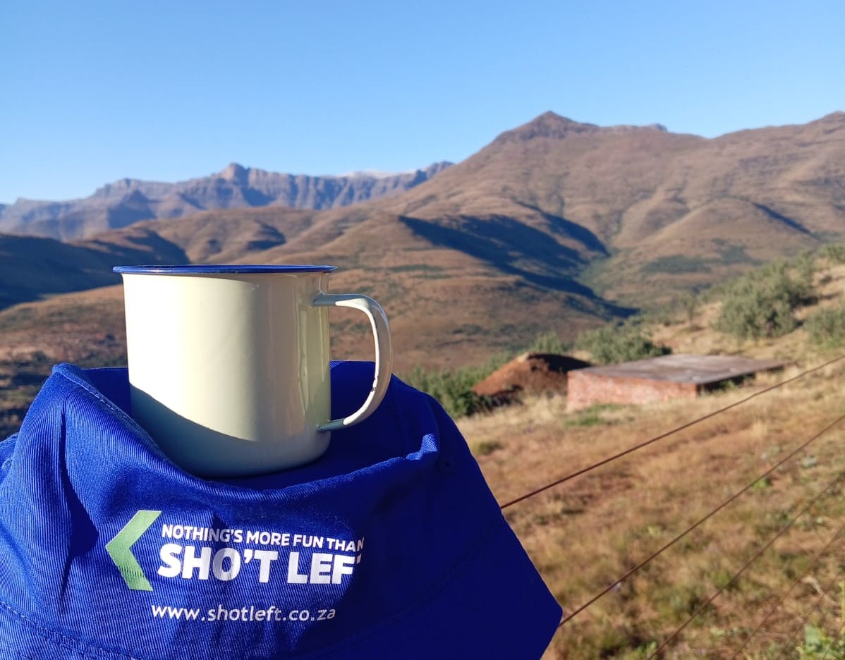 Enamel mug on cap overlooking mountain landscape