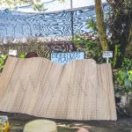 Woven mat beside indigenous plants garden sign