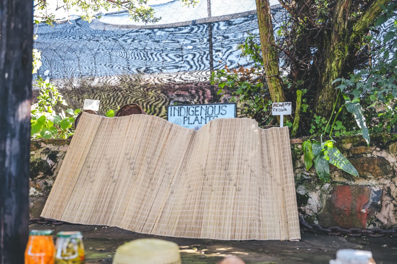 Woven mat beside indigenous plants garden sign