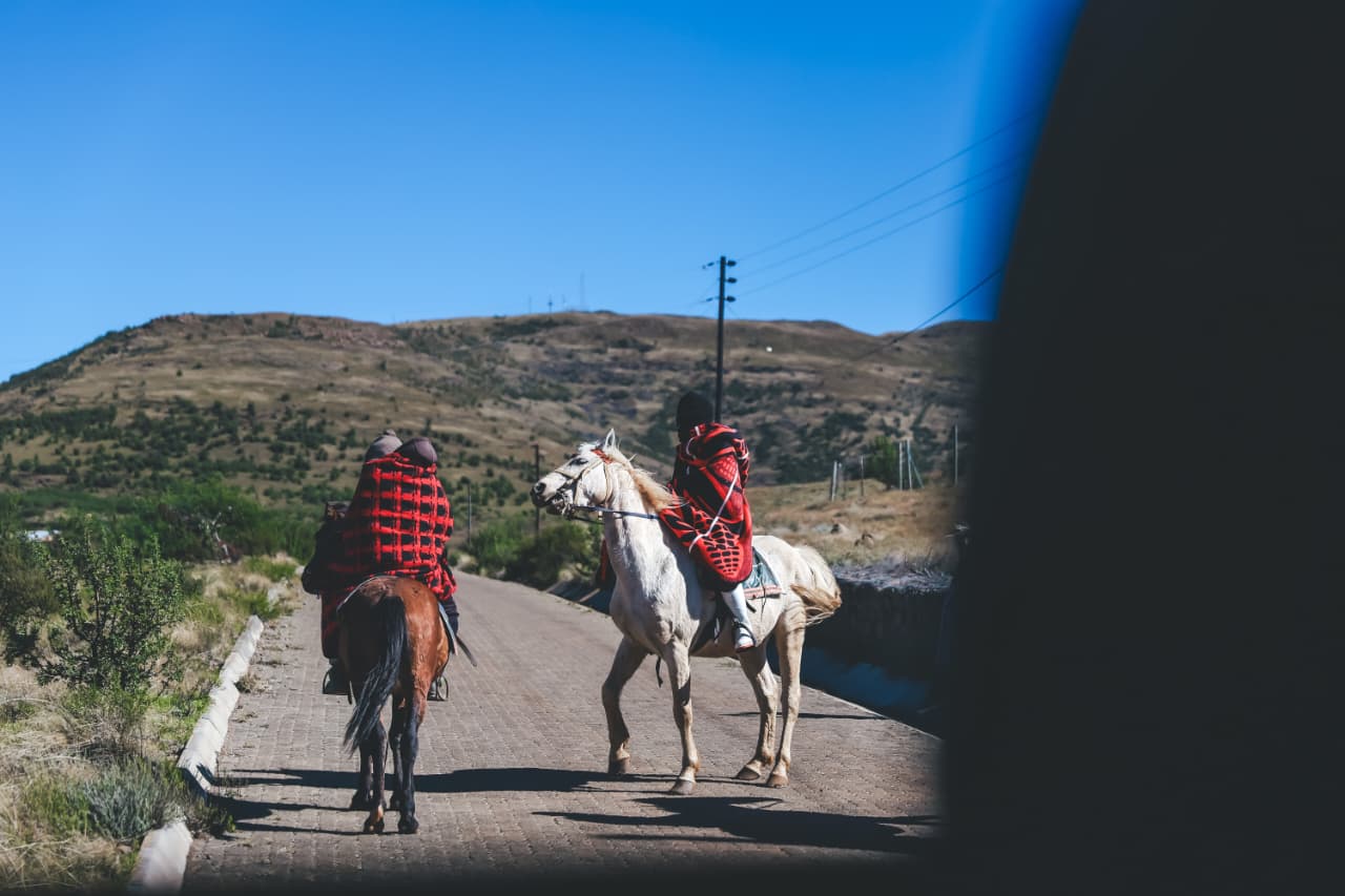 Two riders on horses along rural mountain road