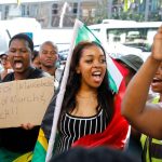 Protesters marching with South African flag and placard