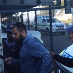 Police officers escort man into police vehicle