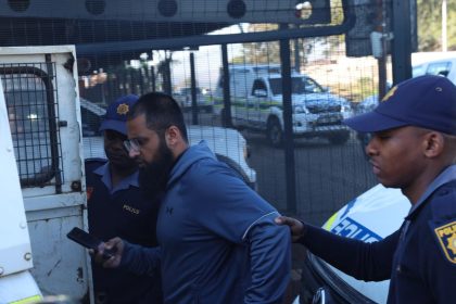 Police officers escort man into police vehicle