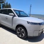 White electric MPV parked by seaside promenade