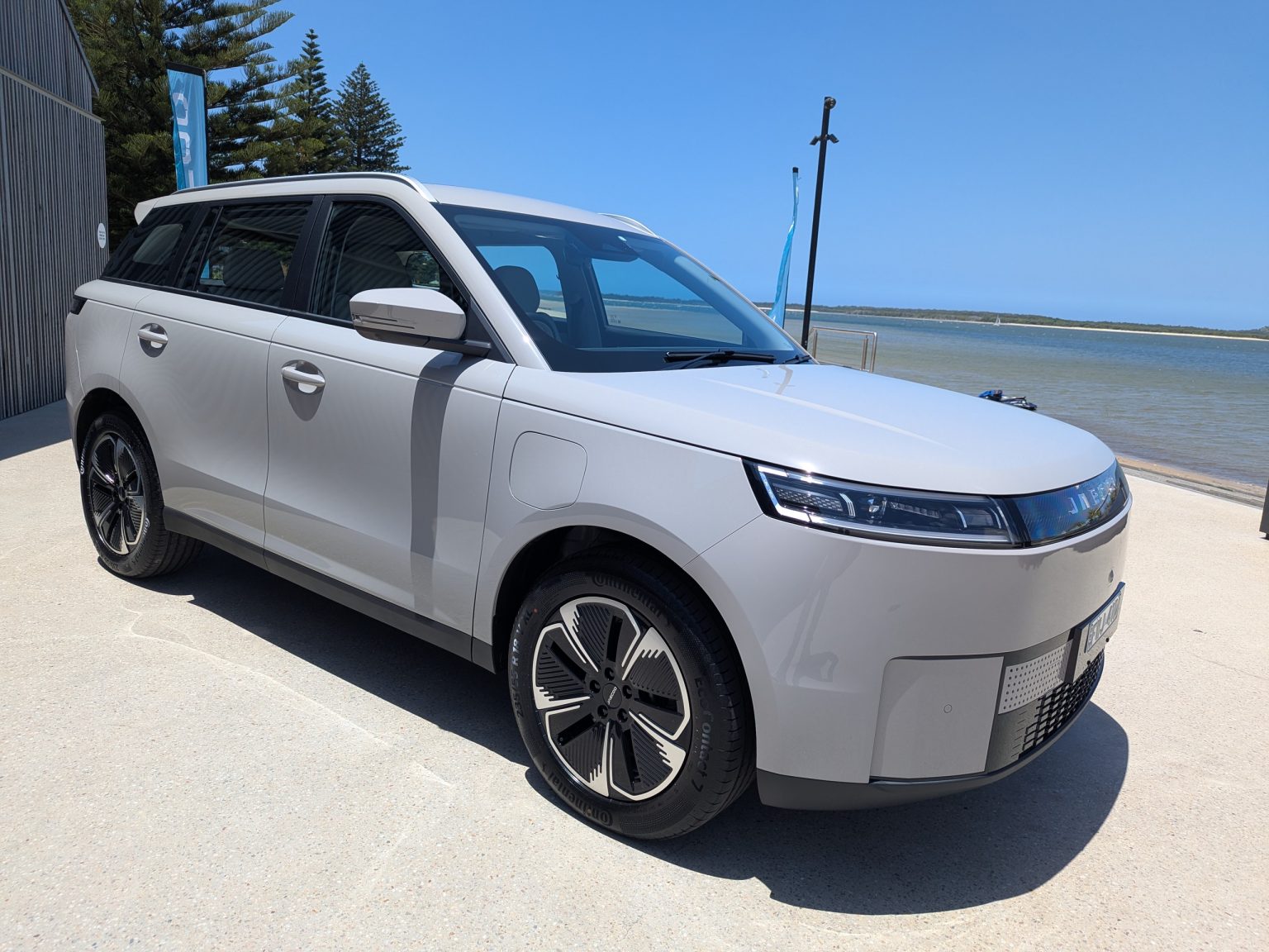 White electric MPV parked by seaside promenade