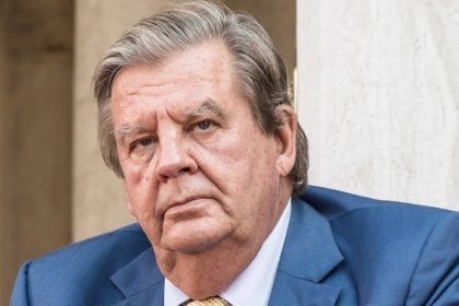 Older man in blue suit with serious expression