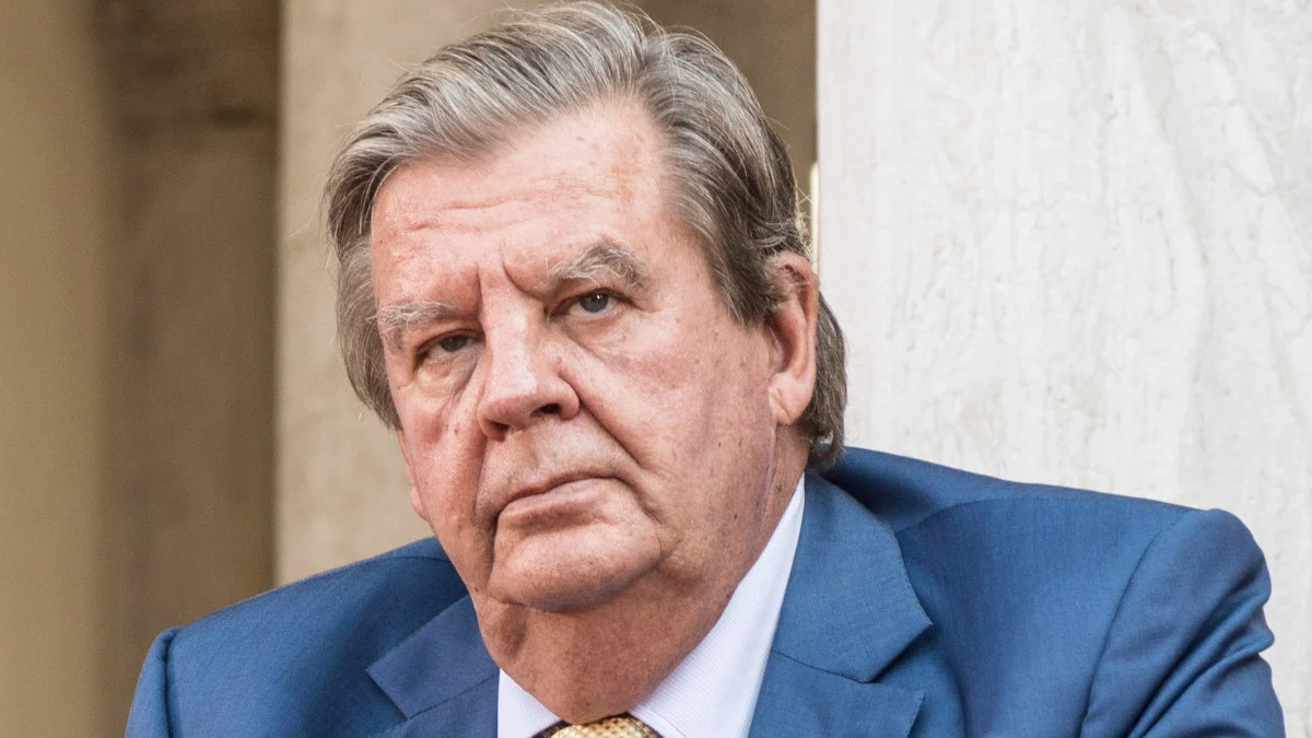 Older man in blue suit with serious expression