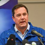 Man speaking at podium before party backdrop