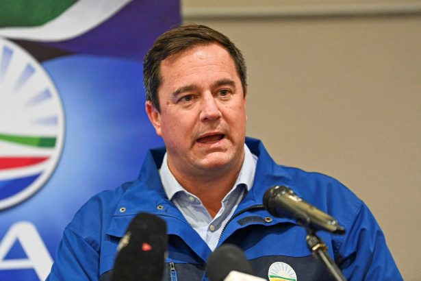 Man speaking at podium before party backdrop