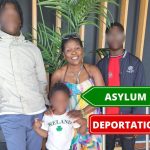Family standing indoors with asylum and deportation signs
