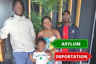 Family standing indoors with asylum and deportation signs