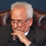 Older man in suit sitting thoughtfully in leather chair