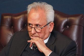 Older man in suit sitting thoughtfully in leather chair