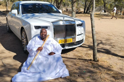 Man in white robe before luxury car