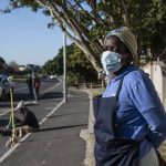 Masked woman standing on suburban roadside