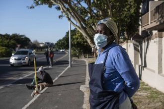 Masked woman standing on suburban roadside