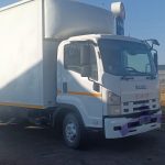 White Isuzu box truck parked near petrol station