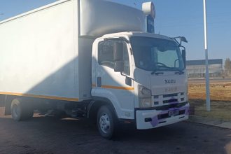 White Isuzu box truck parked near petrol station