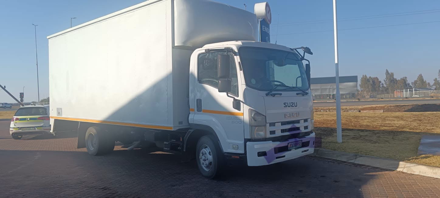 White Isuzu box truck parked near petrol station