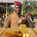 Soldier speaking behind stacked gold bars display