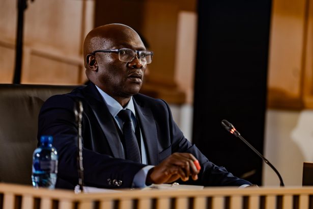 Man in suit speaking at formal hearing
