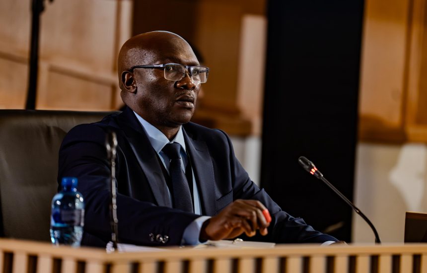 Man in suit speaking at formal hearing