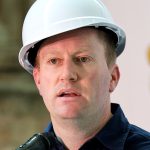 Man in hard hat speaking at podium