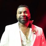 Man in white suit under red stage lighting