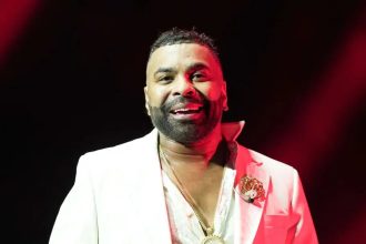 Man in white suit under red stage lighting