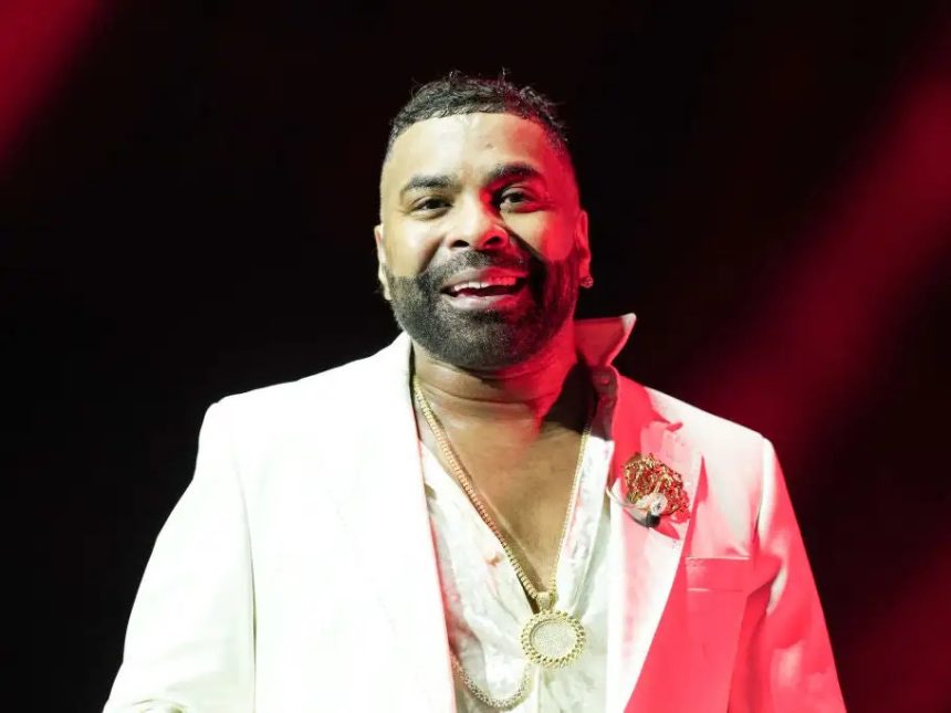 Man in white suit under red stage lighting