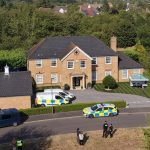 Police vehicles outside large suburban brick house