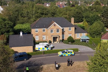 Police vehicles outside large suburban brick house