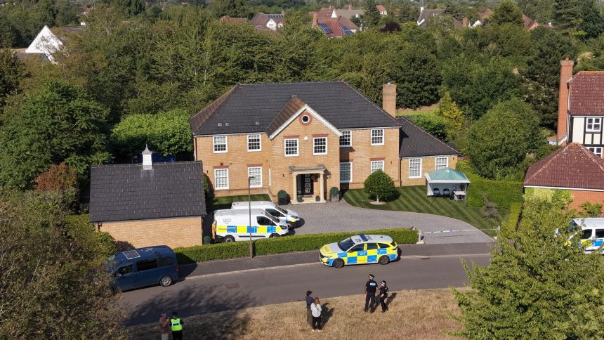 Police vehicles outside large suburban brick house