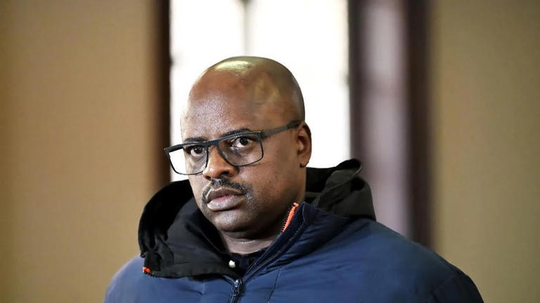 Man wearing glasses and dark jacket indoors