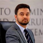 Man in suit seated at commission hearing