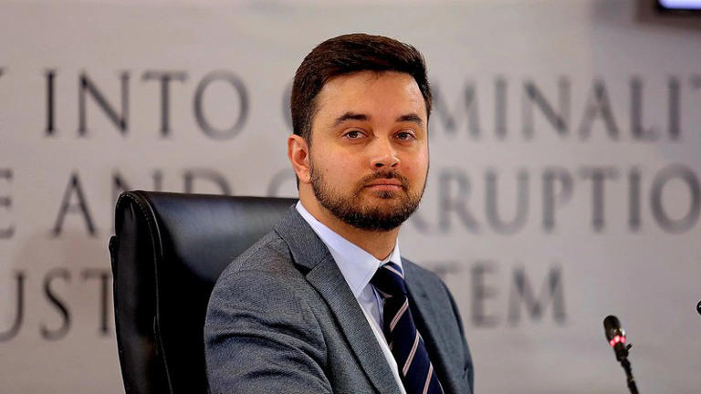 Man in suit seated at commission hearing