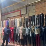 Clothing display with trousers and outfits on wall
